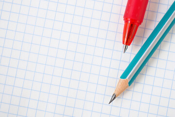 Light background on the theme of schooling with place for text. Wooden pencil and red pen lie on a blank notebook sheet close-up. Backdrop on the theme of studying at school and higher education