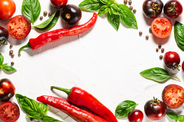 Creative layout made with ripe tomatoes,fresh aromatic basil. hot chili pepper and allspice on white stone background. Cooking book cover template.
