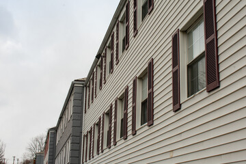Repeating Windows With Brown Shutters on a White Apartment Building