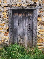 Old wooden door on a facade of a stone house