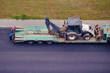 Loading the excavator onto the platform of a construction equipment transport truck