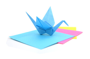 A blue origami crane with paper sheets