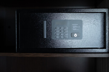 Small black safe in hotel room with digital code