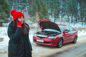 woman calling for help with broken down car at winter highway