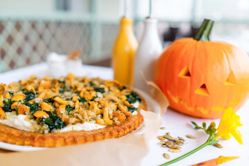 Pumpkin pie with chanterelles. A carved pumpkin in the background. Traditional Halloween dish served on a table with a white tablecloth. Top view.