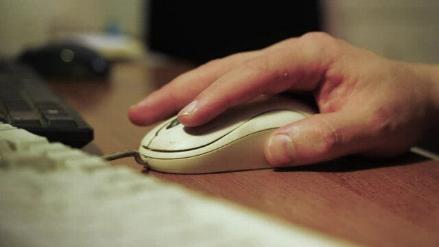 Close-up of man clicking on old computer mouse. Stock footage. Callused hand of office employee working at computer. Man uses old computer equipment