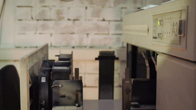 Office worker working with printing machines. Stock footage. Close-up of office worker putting paper in typewriter. Large amount of paper is put in printing machine