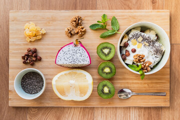 Fruit salad in a bowl and its ingredients arranged on a wooden board