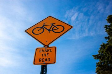  Bug eye view of a yellow rhombus road sign with a bicycle symbol, and a plate attached underneath which says 'share the road'