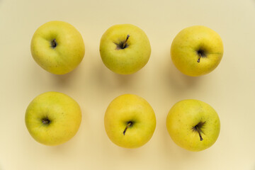 6 golden delicious apples on a yellow background