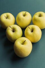 golden delicious apples set in a triangle on a green background