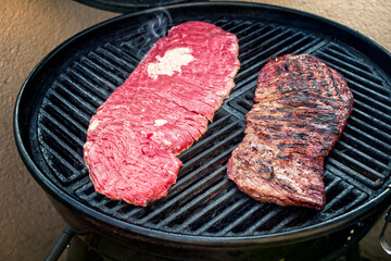 Barbecue wagyu bavette beef steak preparing as close-up on a kettle grill with cast iron grillage