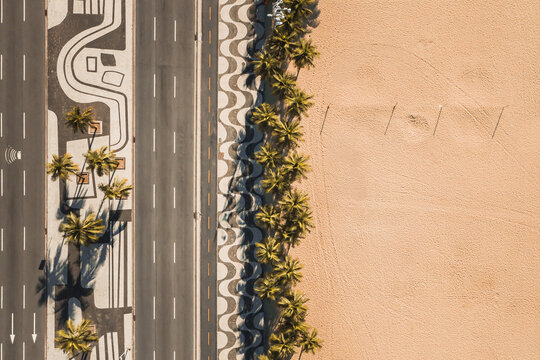 Aerial Top Down View Of Palm Trees On Empty Copacabana Beach, Alongside Famous Mosaic Sidewalk And Avenida Atlantica Road, During Coronavirus Lockdown In Rio De Janeiro, Brazil