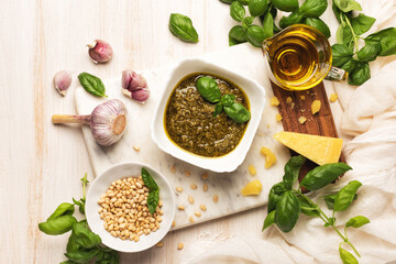 Bowl with pesto with pasta and fresh basil, garlic, parmesan cheese, pine nuts and olive oil on marble board. Kitchen wooden table with Italian sauce