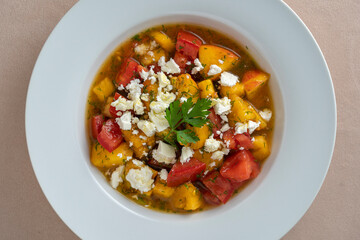 Colorful summer salad with tomato, peach and feta cheese , close up