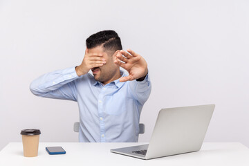 No, don't want to look! Businessman sitting office workplace with laptop on desk, covering eyes showing stop gesture, avoiding watch something unpleasant. studio shot isolated on white background