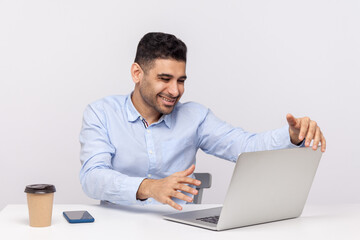 Fototapeta na wymiar Free hugs online! Happy friendly businessman sitting office workplace, stretching hands to laptop screen, going to embrace, welcoming on conference. indoor studio shot isolated on white background