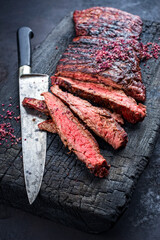 Barbecue wagyu bavette beef steak with red wine salt offered as close-up on charred wooden black...