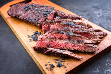 Gegrilltes Wagyu Bavette Steak vom Rind mit Rotwein Salz angeboten als close-up auf einem rustikalen Modern Design Holz Board