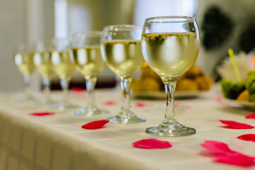 Glass wine glasses stand in row on the table. Blurred background.