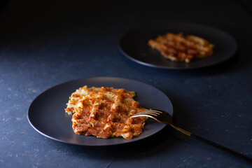 toasted Viennese zucchini waffles on two black plates on a dark concrete background.