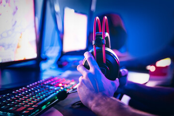 Professional cyber gamer playing online tournaments computer with headphones, Blurred Red and Blue background