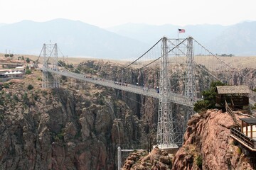 People Walking Over Royal Gorge Bridge With American Flag Flying In Wind