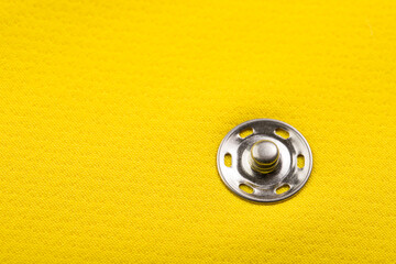details of clothing made of yellow plain fabric, button closure element, pinning the entrance to the side pocket
