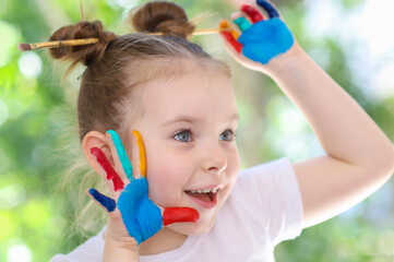 Funny cute little girl with her hands stained in paint. The concept of children's creativity. High quality photo