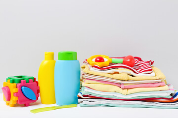 Colorful clothes with toys and baby supplies on white background