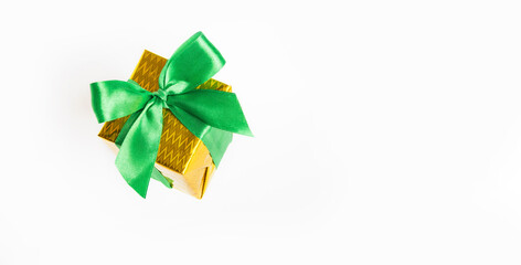 Shiny yellow gift box with green ribbon isolated on white background.