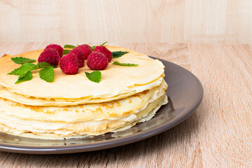 Pancakes with raspberries. Pancakes with raspberries on a brown plate. Pancakes with raspberries on a plate and a wooden board.