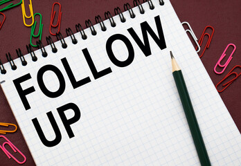 Design concept - Top view of white spiral notebook and pencil with text FOLLOW UP isolated on red background for mockup