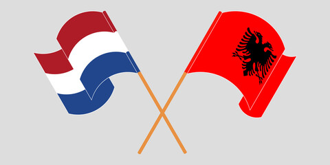 Crossed and waving flags of Albania and the Netherlands