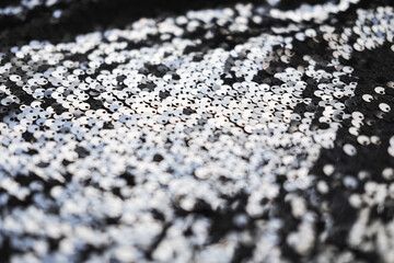 Sequin fabric texture. Shiny silver sparkling background. Clothing piece of glitter metallic for a glamorous party, celebration. Close-up.