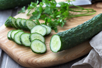 Long Chinese cucumbers on a cutting board while slicing salad. wood background. selective focus