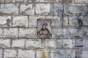 Fototapeta na wymiar Old iron ring in a metal loop on a stone wall