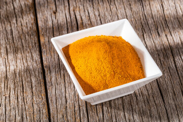 turmeric powder in bowl on old wooden background
