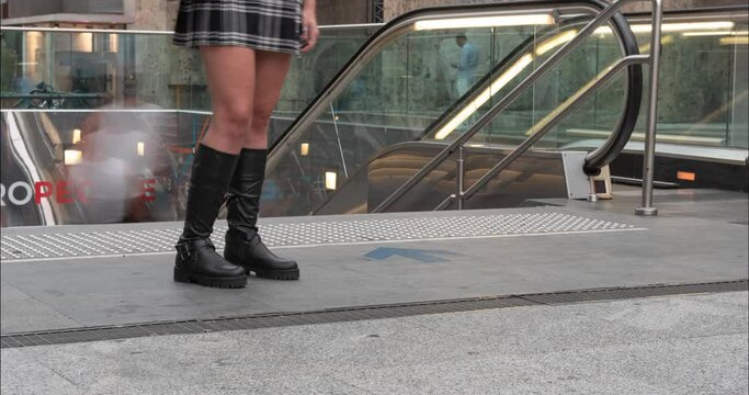 Legs of a young woman at the entrance to the subway. Miniskirt. Boots.