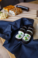 Set of traditional japanese food on a dark background. Sushi rolls, nigiri, raw salmon steak, rice, cream cheese, avocado, lime, pickled ginger. Asian food frame.