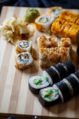 Set of traditional japanese food on a dark background. Sushi rolls, nigiri, raw salmon steak, rice, cream cheese, avocado, lime, pickled ginger. Asian food frame.