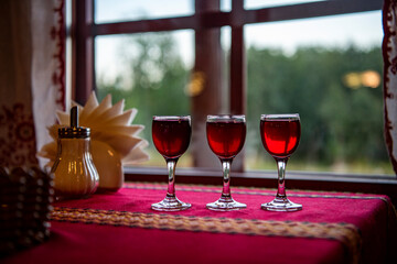 eyelets with red liqueur on the table with a red tablecloth against the background of the window