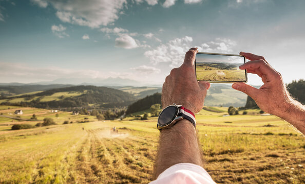 Tourist man taking photo of landscape with smartphone