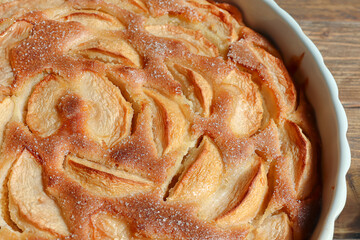 Traditional french homemade apple pie in a white ceramic baking form close-up