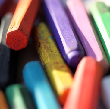 Box filled with all colors of oil pastel crayons