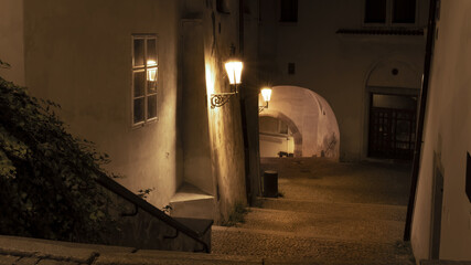 Night photo from the stairs to the dark arcade with the reflection of an old lamp in the window