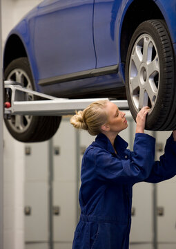 Female car mechanic working in busy garage.