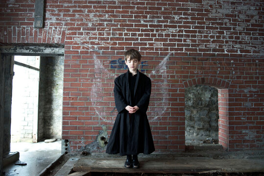 Boy stands quietly in abandoned building with eyes closed