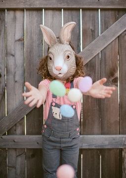 Little girl wearing bunny mask playing with Easter Eggs