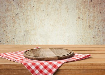 Wooden cutting board and tablecloth on wooden table
